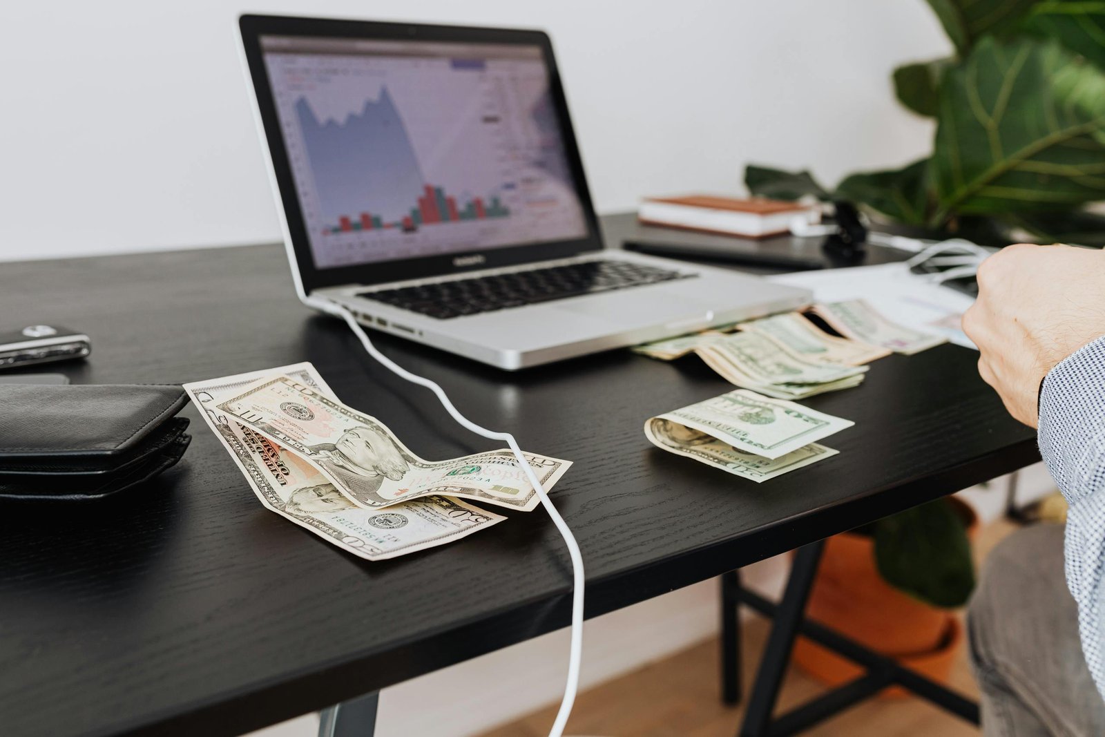 A workspace with cash, laptop, and financial graph showing investment analysis.