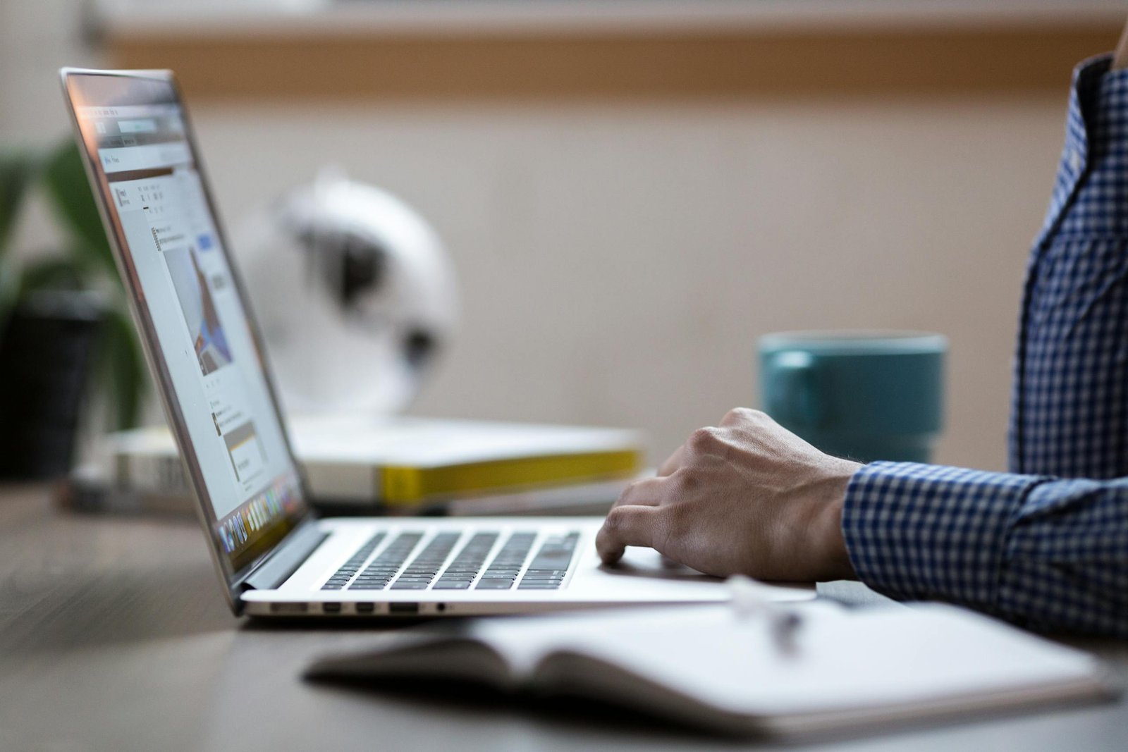 Business professional working on laptop at an office desk with coffee mug.