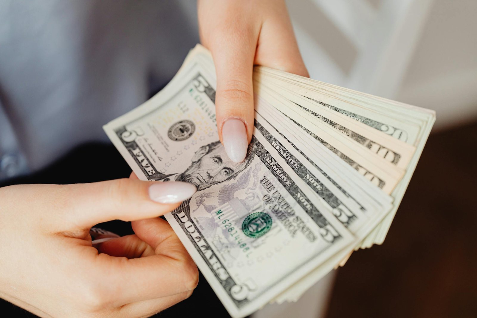 Hands count US dollar bills, showcasing finance and cash handling concepts.