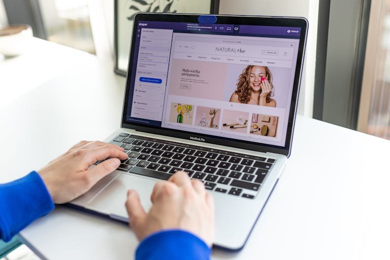 Hands typing on a laptop with an e-commerce website open, showcasing online shopping.