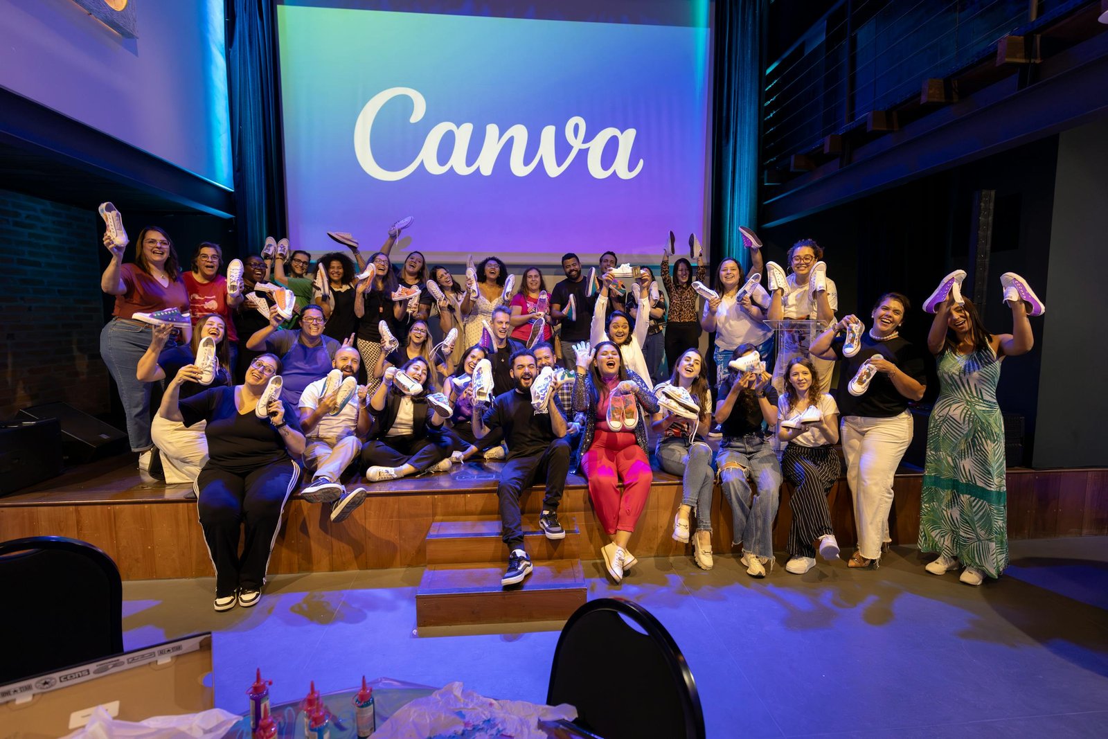 Large group celebrating with personalized shoes at a Canva event indoors